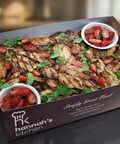 Chargrilled balsamic chicken breast platter with cherry tomatoes and fresh greens in Hannah’s Kitchen catering box