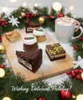Festive Adult Toy Show Treat Box by Hannah’s Kitchen with brownies, blondies, mini Christmas puddings, and hot chocolate surrounded by Christmas garland and lights.