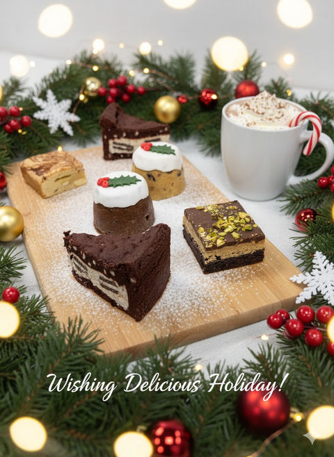 Festive Adult Toy Show Treat Box by Hannah’s Kitchen with brownies, blondies, mini Christmas puddings, and hot chocolate surrounded by Christmas garland and lights.