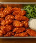 Buffalo chicken wings in catering tray with fresh rocket leaves and dip from Hannah’s Kitchen Cork.