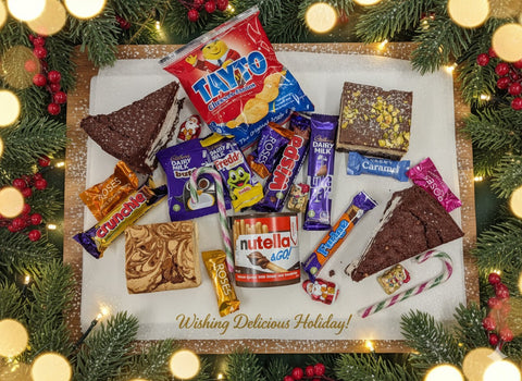 Festive Late Late Toy Show Treat Box from Hannah’s Kitchen featuring Tayto crisps, Cadbury chocolates, Nutella, brownies, blondies, and Christmas sweets surrounded by holiday decorations.